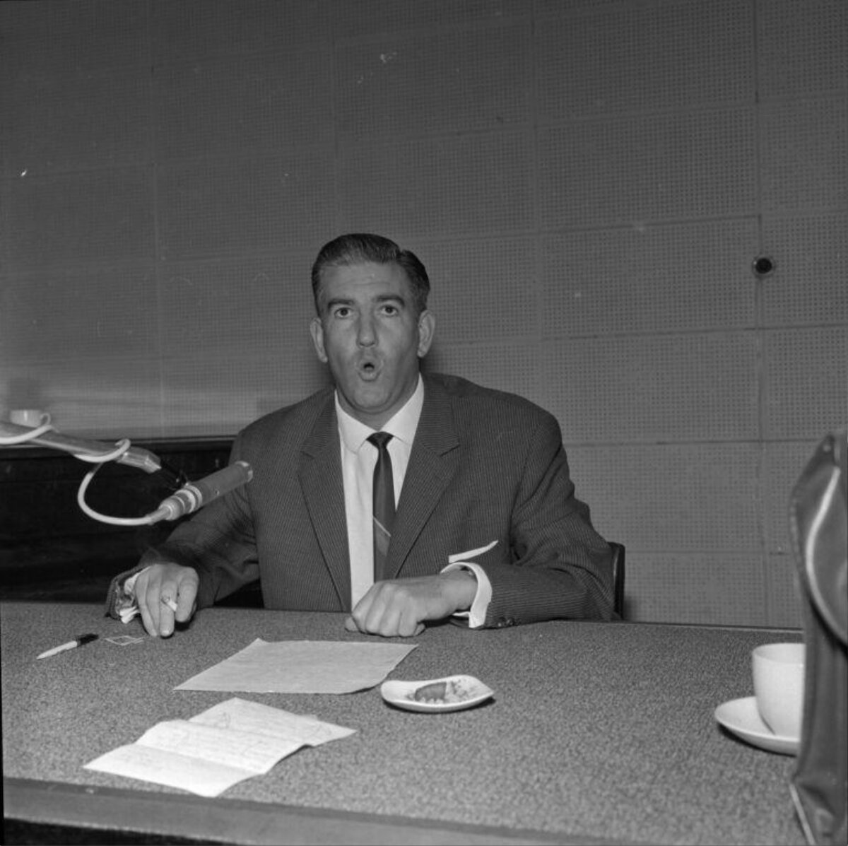 Man Speaking Into Microphone at Desk